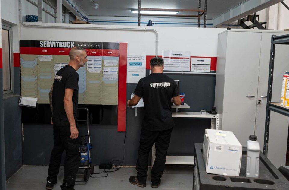 Empleados de Servitruck organizando y revisando documentos en la oficina del taller