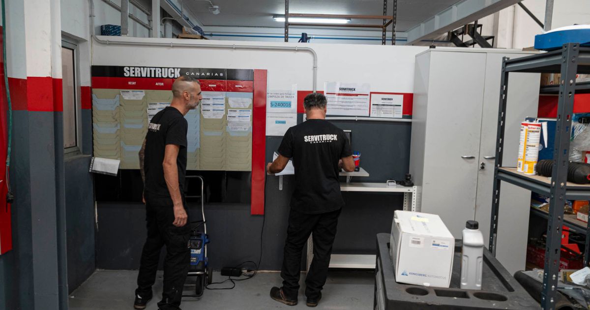 Empleados de Servitruck organizando y revisando documentos en la oficina del taller