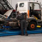 Mecánico de Servitruck inspeccionando el chasis de un vehículo industrial sobre una plataforma elevadora.