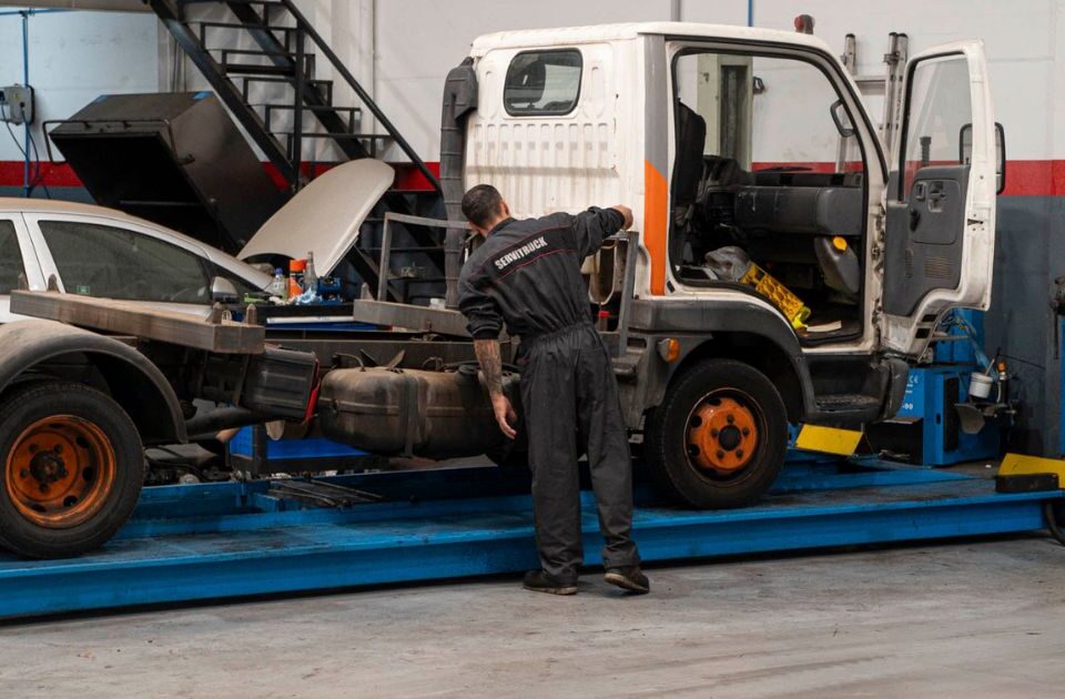 Mecánico de Servitruck inspeccionando el chasis de un vehículo industrial sobre una plataforma elevadora.