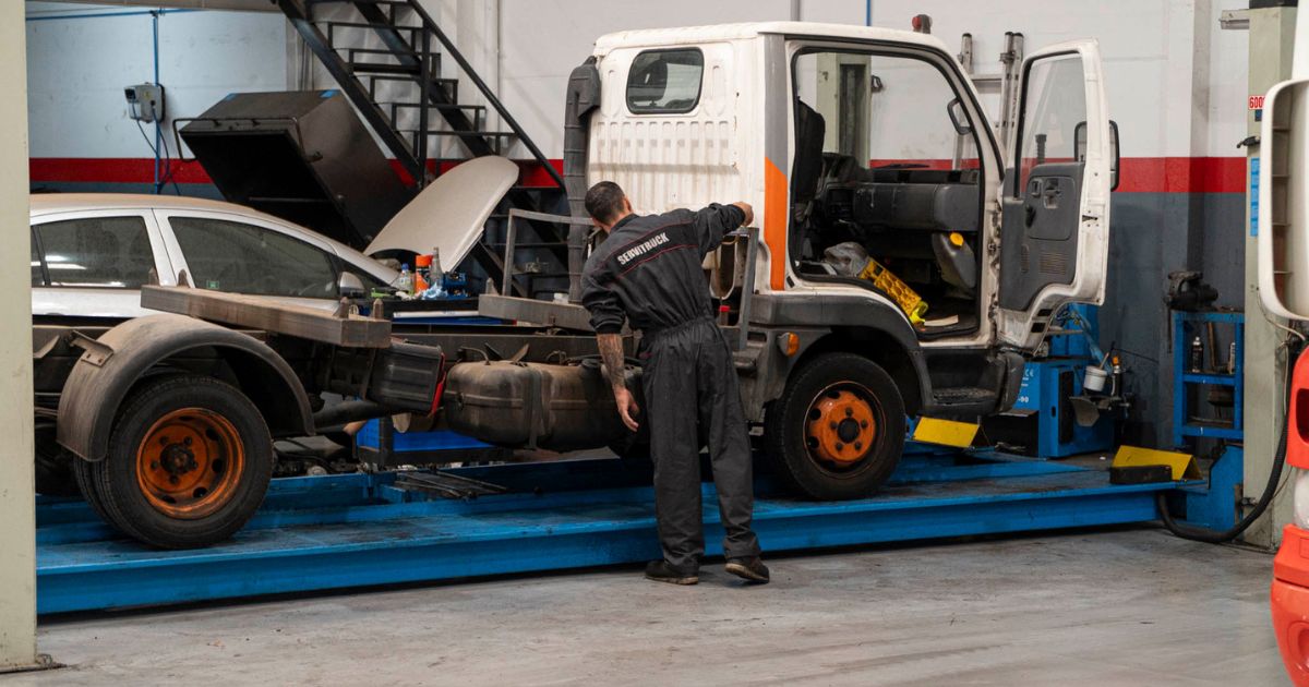 Mecánico de Servitruck inspeccionando el chasis de un vehículo industrial sobre una plataforma elevadora.