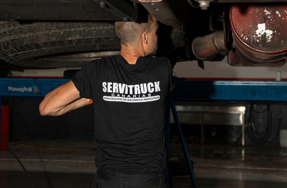 Mecánico de Servitruck trabajando bajo un vehículo industrial, realizando una inspección en el sistema de escape