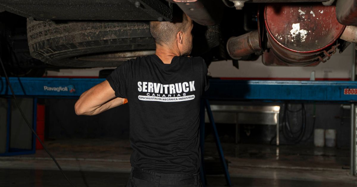 Mecánico de Servitruck trabajando bajo un vehículo industrial, realizando una inspección en el sistema de escape