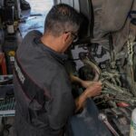 Mecánico de Servitruck trabajando en el motor de un camión con herramientas sobre el compartimento del motor
