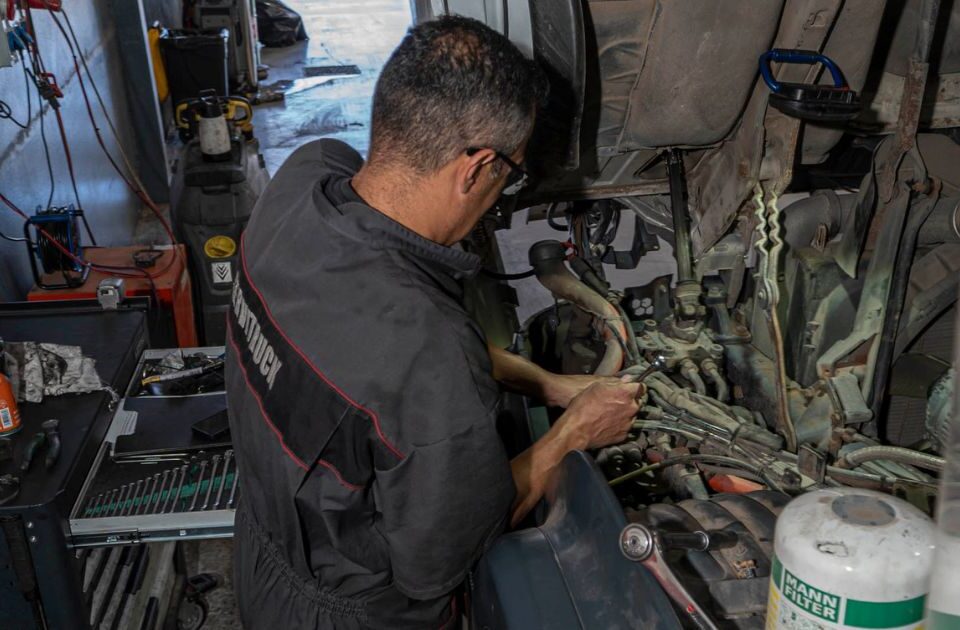 Mecánico de Servitruck trabajando en el motor de un camión con herramientas sobre el compartimento del motor