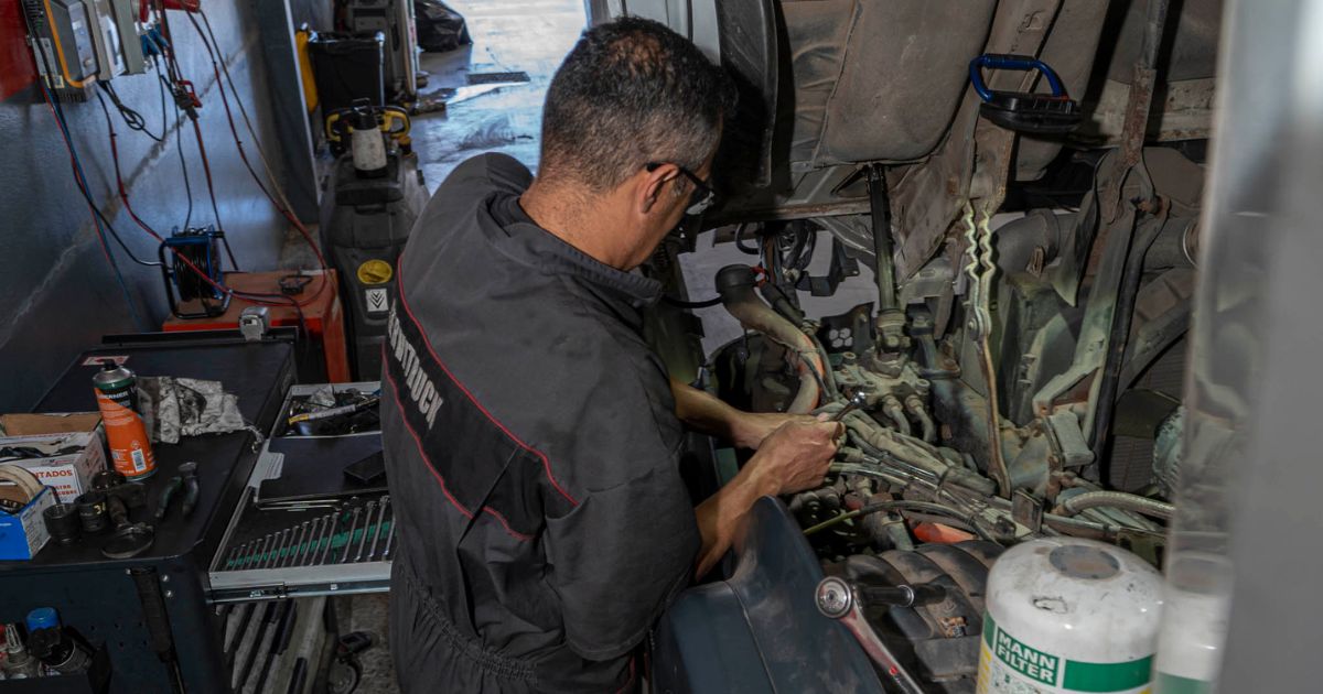 Mecánico de Servitruck trabajando en el motor de un camión con herramientas sobre el compartimento del motor