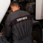 Mecánico de Servitruck trabajando en el motor de un vehículo industrial, realizando una reparación en el taller