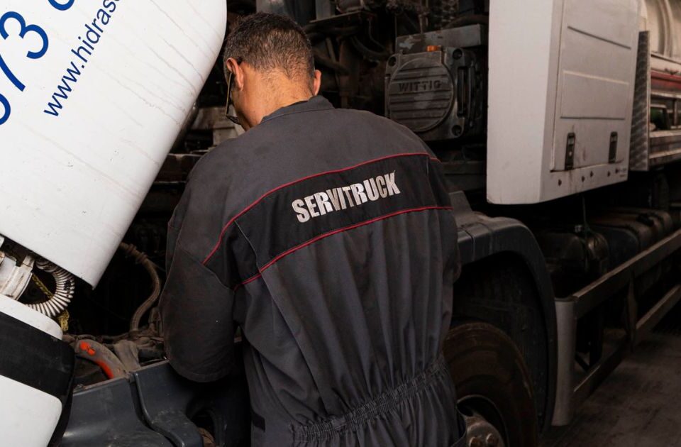 Mecánico de Servitruck trabajando en el motor de un vehículo industrial, realizando una reparación en el taller