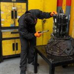 Mecánico de Servitruck trabajando en la reparación de una caja de cambios utilizando una linterna