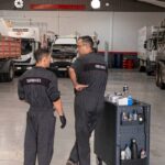 Mecánicos de Servitruck conversando mientras preparan el carrito de herramientas en el taller