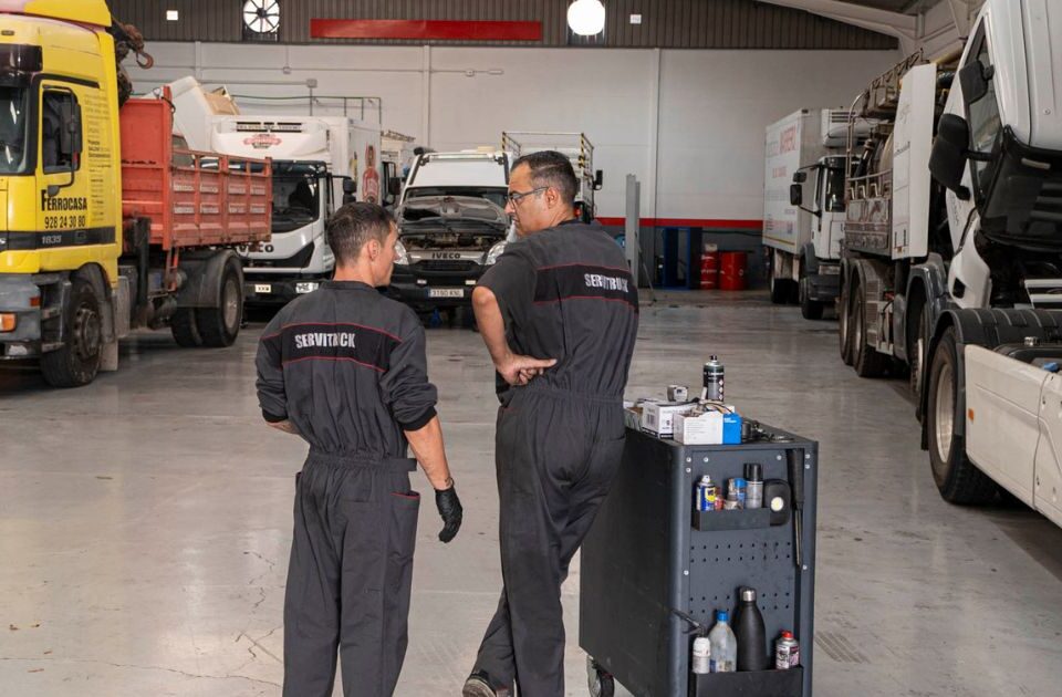 Mecánicos de Servitruck conversando mientras preparan el carrito de herramientas en el taller