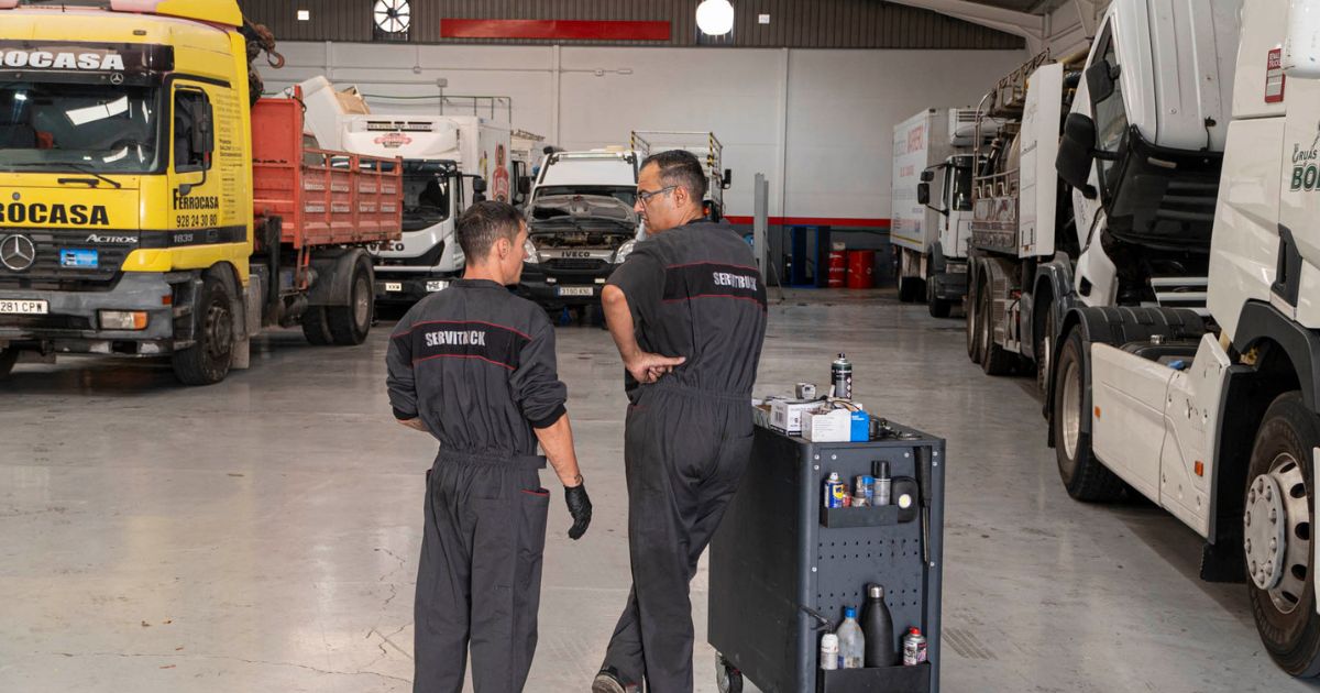 Mecánicos de Servitruck conversando mientras preparan el carrito de herramientas en el taller