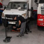 Mecánicos de Servitruck trabajando bajo un vehículo industrial, realizando una inspección en el chasis.