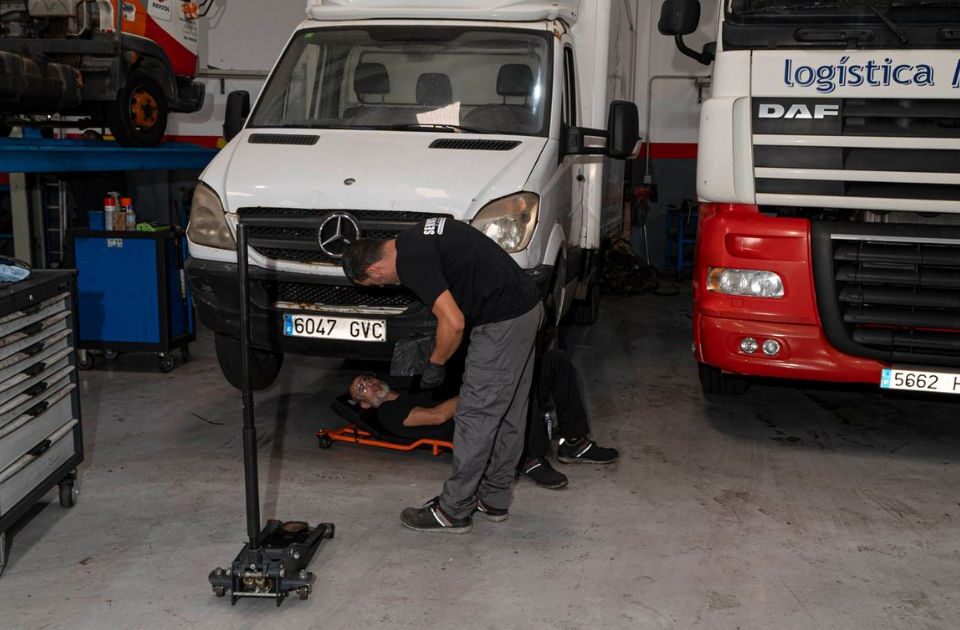 Mecánicos de Servitruck trabajando bajo un vehículo industrial, realizando una inspección en el chasis.